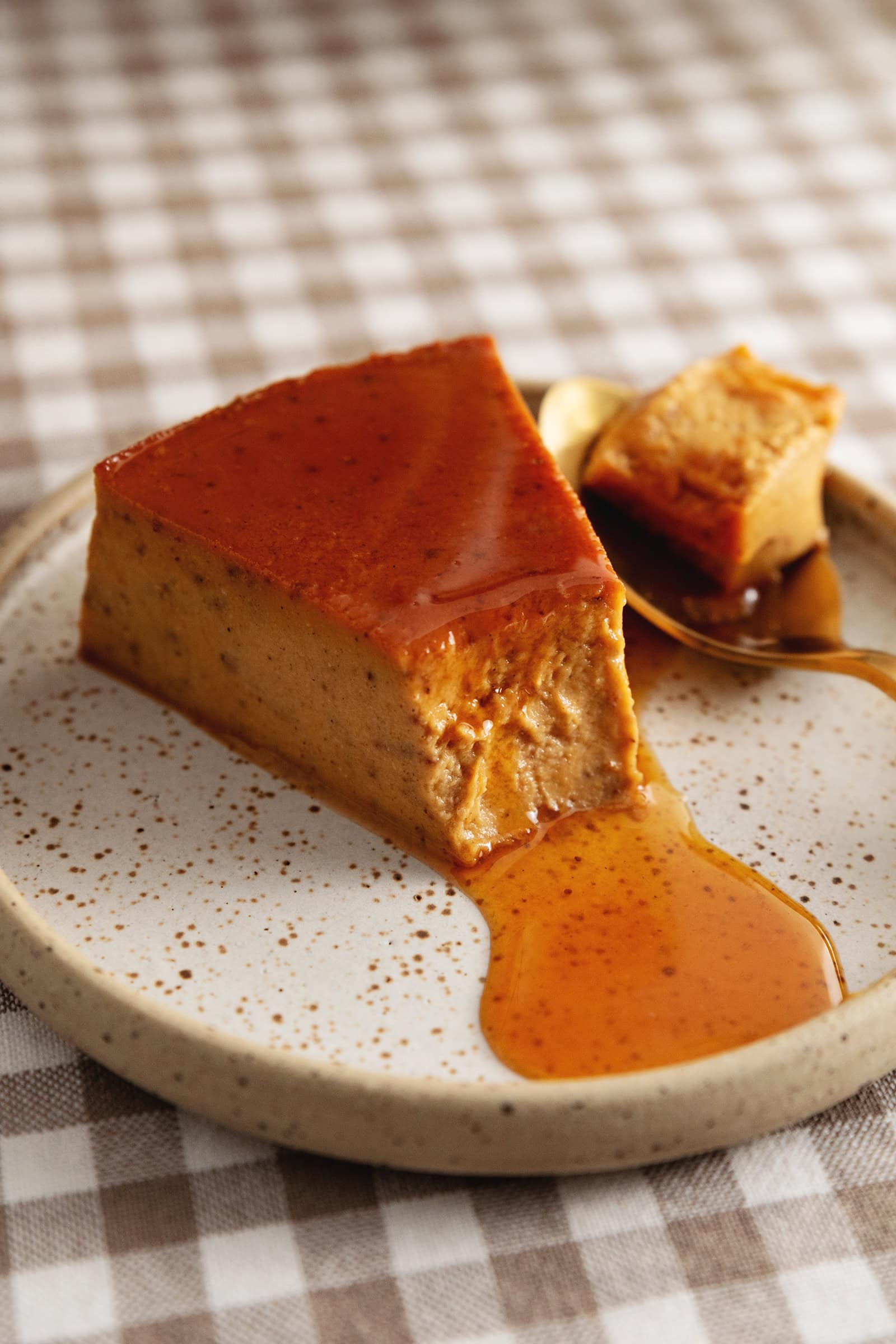 A slice of pumpkin flan with a spoonful taken out of it to show the custard texture.