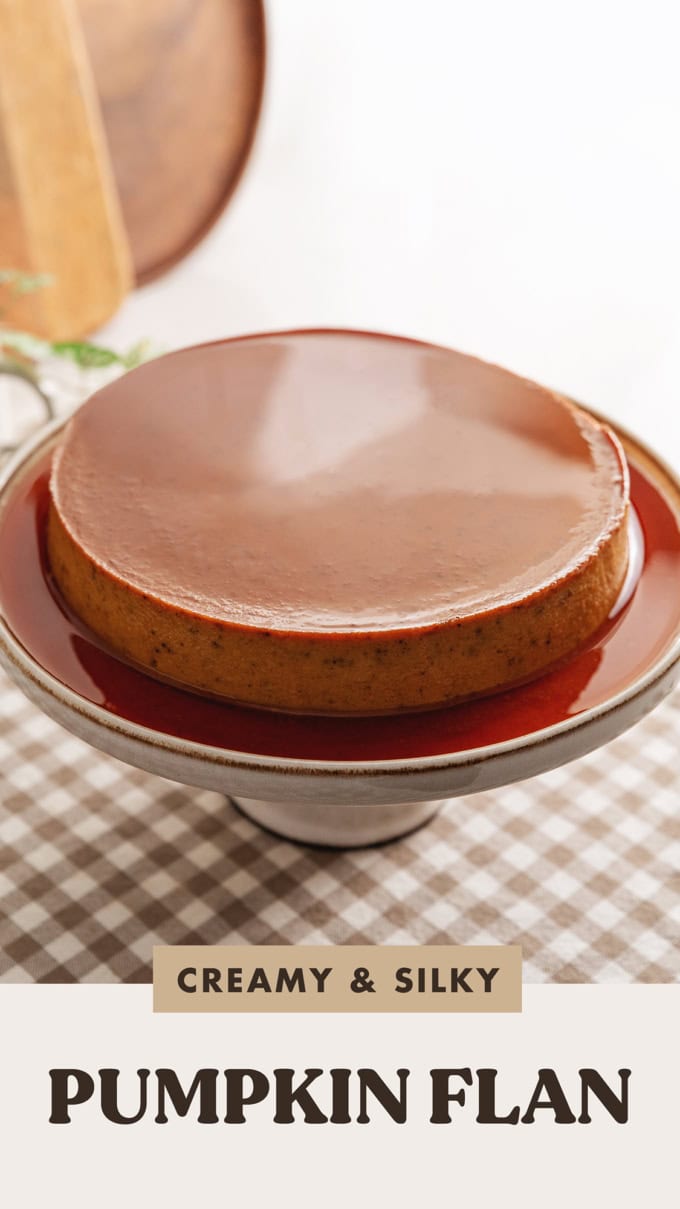 A pumpkin flan on a cake stand with glossy caramel sauce on top and around it.