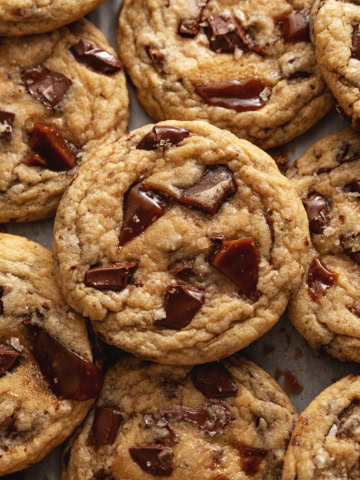 Several toffee cookies slightly overlapping on parchment paper.