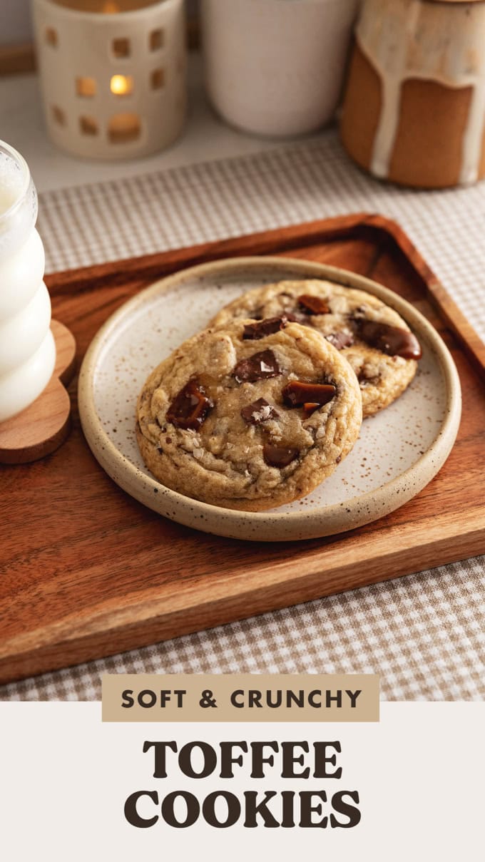 Two toffee cookies on a plate with a glass of milk beside them.