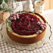 A cranberry orange cheesecake on a cake stand.