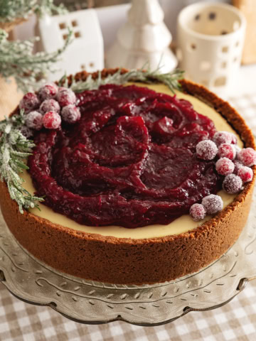 A cranberry orange cheesecake on a cake stand.