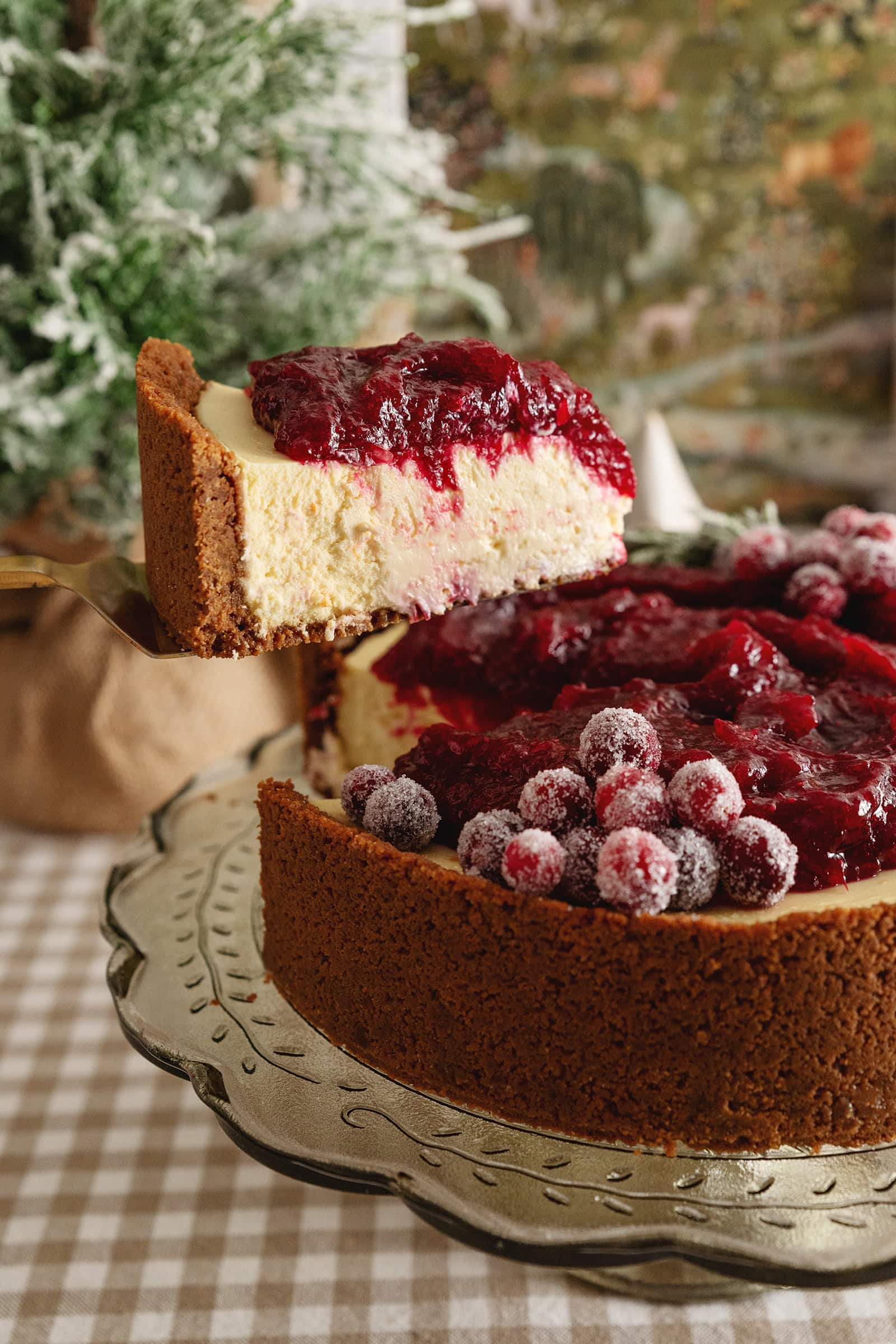 A slice of cranberry orange cheesecake being lifted with a cake server above the rest of the cheesecake.