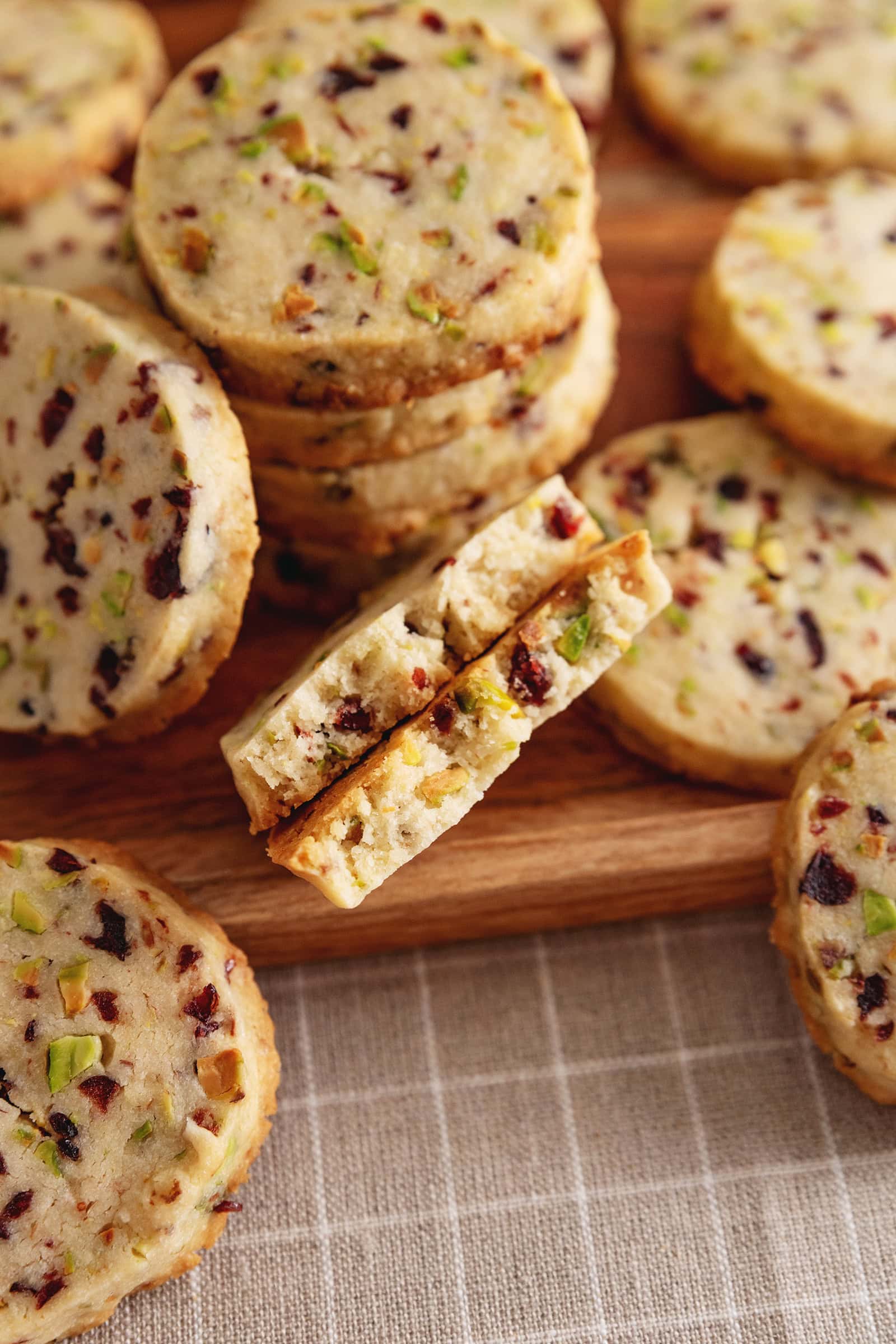 A cranberry pistachio shortbread cookie cut in half to show the texture inside.