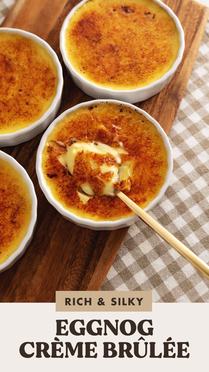 Four ramekins of eggnog crème brûlée with a spoon resting in the custard of one ramekin.