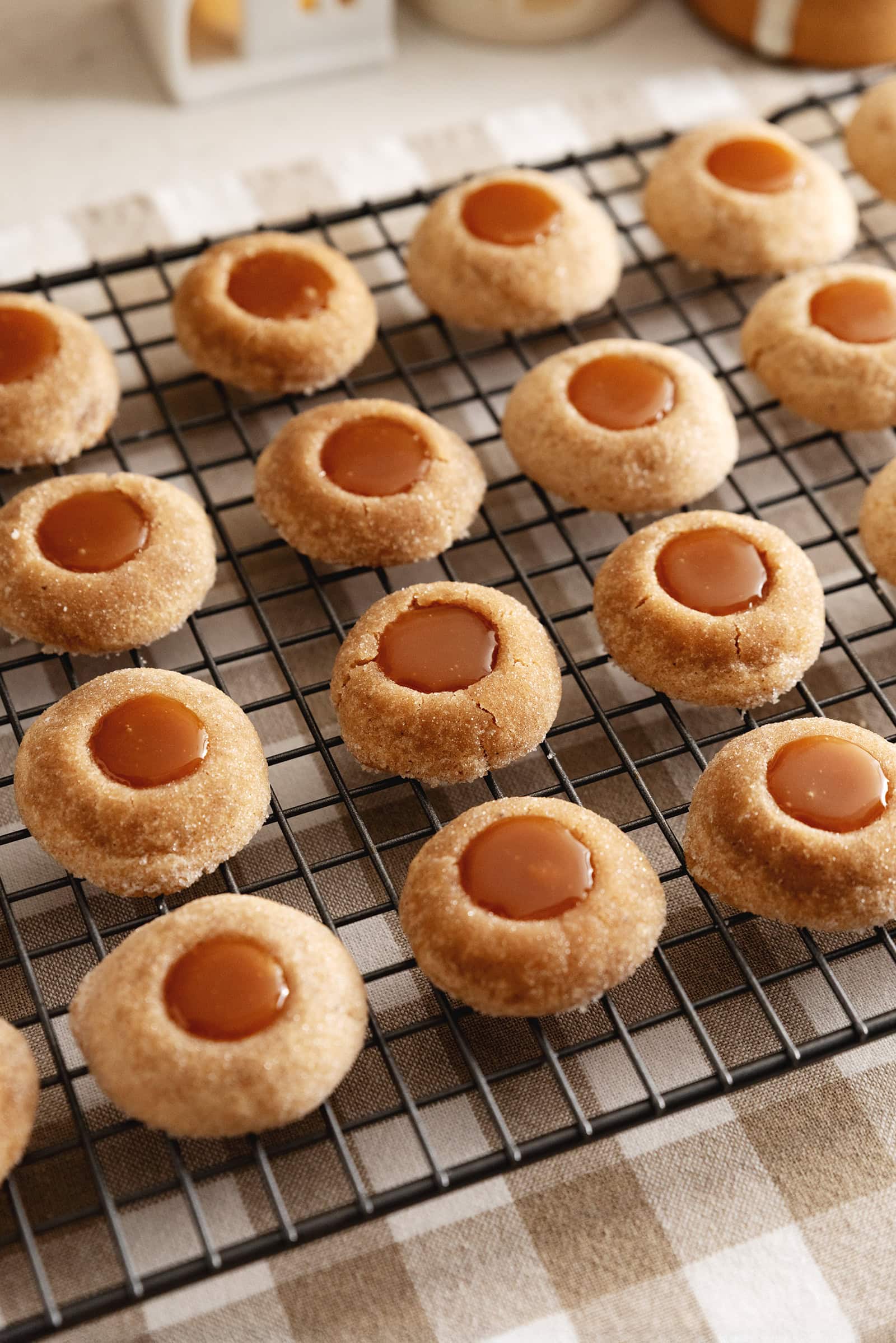 Several gingerbread thumbprint cookies lined up on a wire rack.