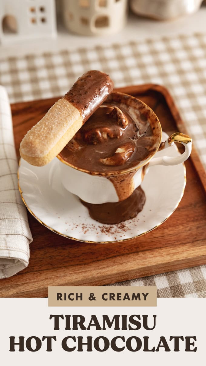 A ladyfinger dipped in tiramisu hot chocolate resting on the edge of the teacup.