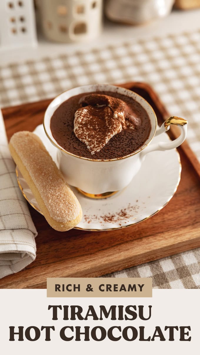 A teacup of tiramisu hot chocolate with a ladyfinger on the saucer.