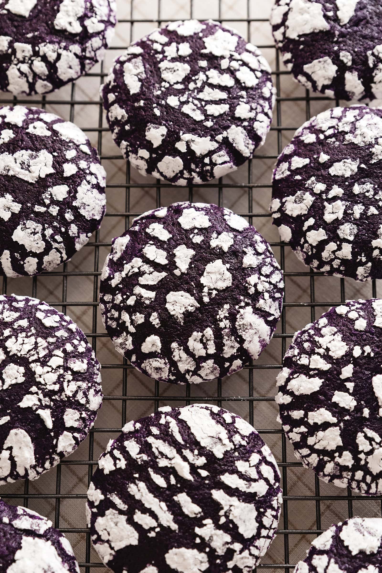 Top down view of ube crinkle cookies lined up on a wire rack.