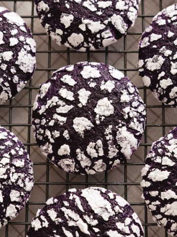 Top down view of ube crinkle cookies lined up on a wire rack.